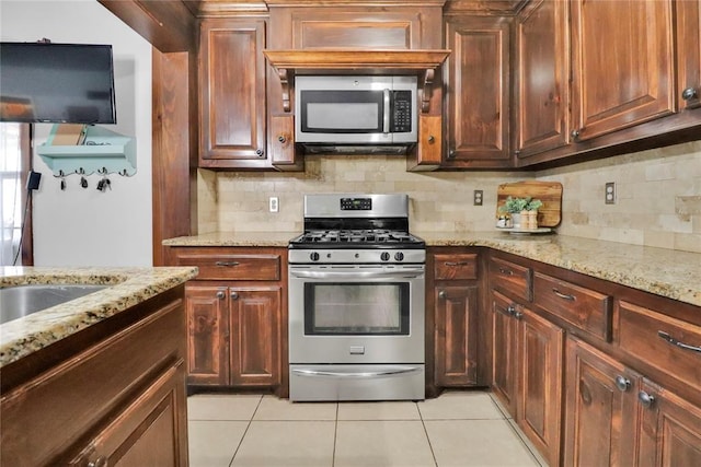 7007 NW 61st St, Bethany, OK 73008 - kitchen featuring stainless steel appliances, backsplash, light tile patterned floors, and light stone counters