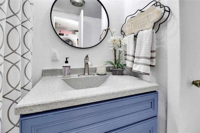7007 NW 61st St, Bethany, OK 73008 - bathroom featuring tile walls, vanity, backsplash, and washer / dryer