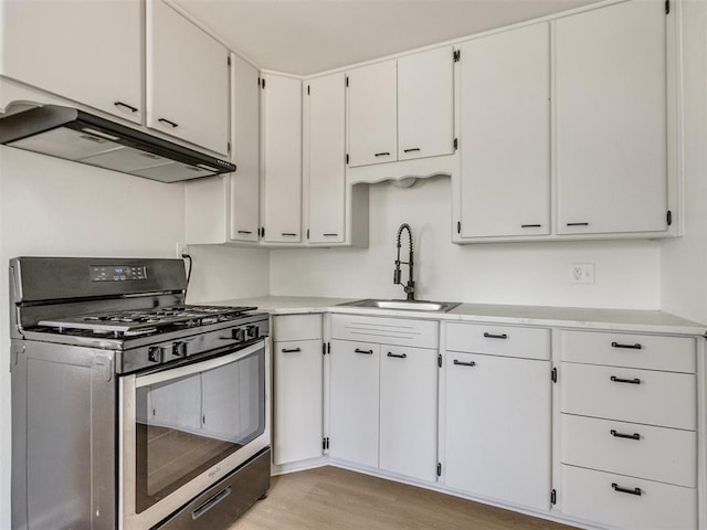 2340 SW 46th St, Oklahoma City, OK 73119 - kitchen with gas stove, under cabinet range hood, light countertops, light wood finished floors, and white cabinetry