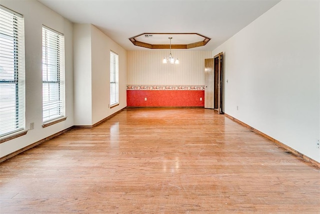 10201 Mantle Ct, Oklahoma City, OK 73162 - empty room featuring a chandelier, light wood-style flooring, and a tray ceiling