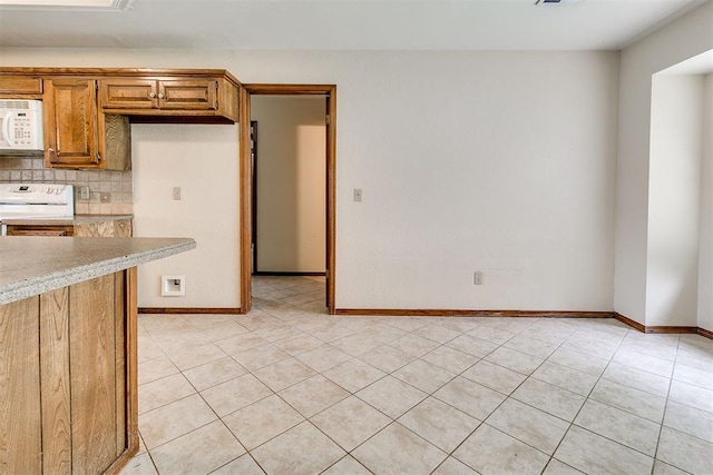 10201 Mantle Ct, Oklahoma City, OK 73162 - kitchen with white microwave, range, light countertops, light tile patterned floors, and tasteful backsplash