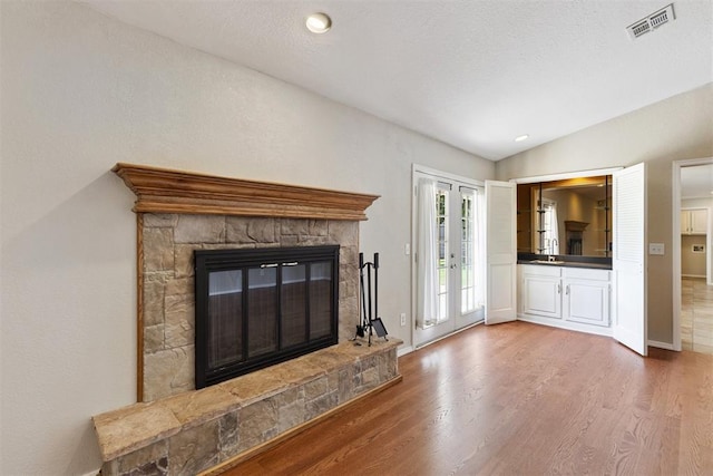 3000 Middlesex Dr, Oklahoma City, OK 73120 - unfurnished living room featuring a stone fireplace, wood finished floors, lofted ceiling, french doors, and recessed lighting
