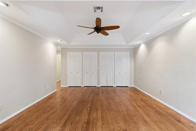 3000 Middlesex Dr, Oklahoma City, OK 73120 - unfurnished bedroom with a raised ceiling, crown molding, two closets, wood finished floors, and recessed lighting