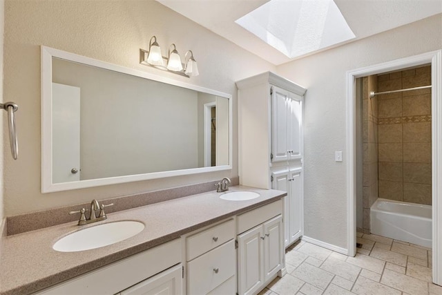 3000 Middlesex Dr, Oklahoma City, OK 73120 - full bathroom featuring a skylight, double vanity, bathtub / shower combination, a textured wall, and stone tile flooring