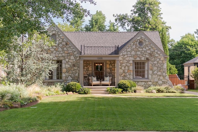 1005 NW 40th St, Oklahoma City, OK 73118 - tudor-style house featuring stone siding, a front lawn, a high end roof, and a porch