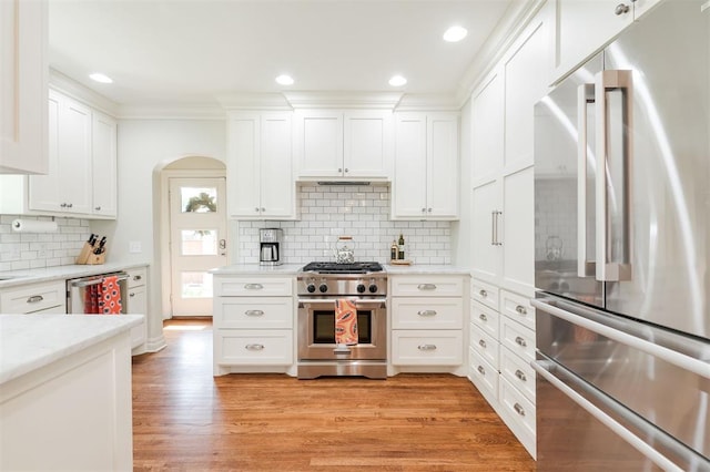 1005 NW 40th St, Oklahoma City, OK 73118 - kitchen with high quality appliances, white cabinetry, decorative backsplash, arched walkways, and light wood-type flooring