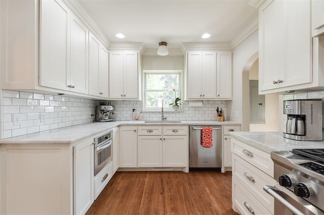1005 NW 40th St, Oklahoma City, OK 73118 - kitchen with appliances with stainless steel finishes, wood finished floors, arched walkways, white cabinetry, and tasteful backsplash