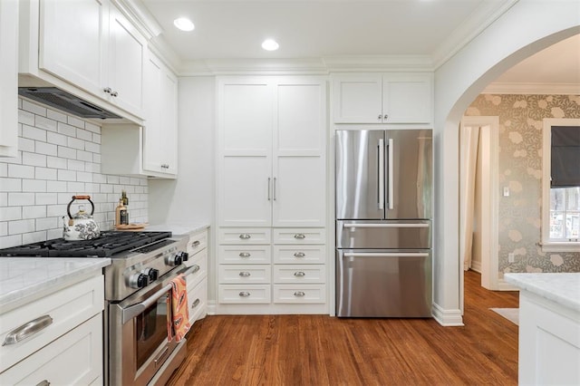 1005 NW 40th St, Oklahoma City, OK 73118 - kitchen featuring appliances with stainless steel finishes, arched walkways, dark wood-style flooring, white cabinets, and light stone countertops