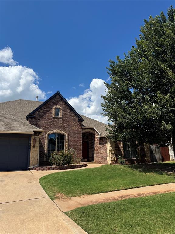 9209 SW 28th St, Oklahoma City, OK 73128 - view of front of house with driveway, an attached garage, brick siding, and roof with shingles