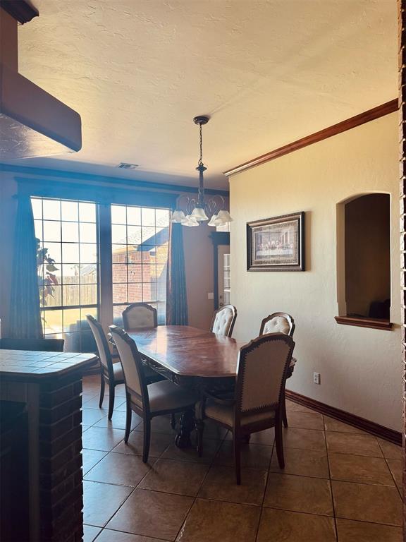 9209 SW 28th St, Oklahoma City, OK 73128 - tiled dining area featuring a chandelier, ornamental molding, and a textured ceiling