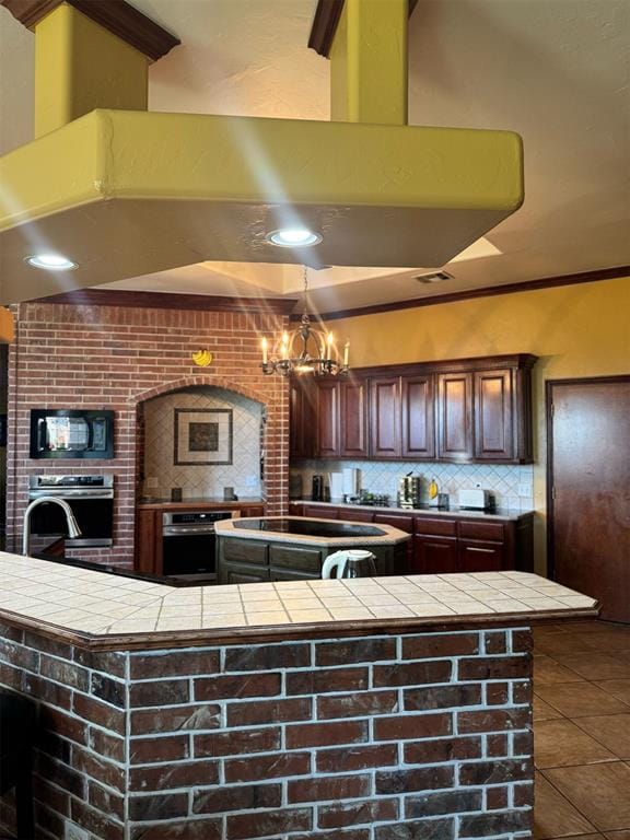 9209 SW 28th St, Oklahoma City, OK 73128 - kitchen with stainless steel oven, black microwave, decorative backsplash, tile countertops, and a chandelier