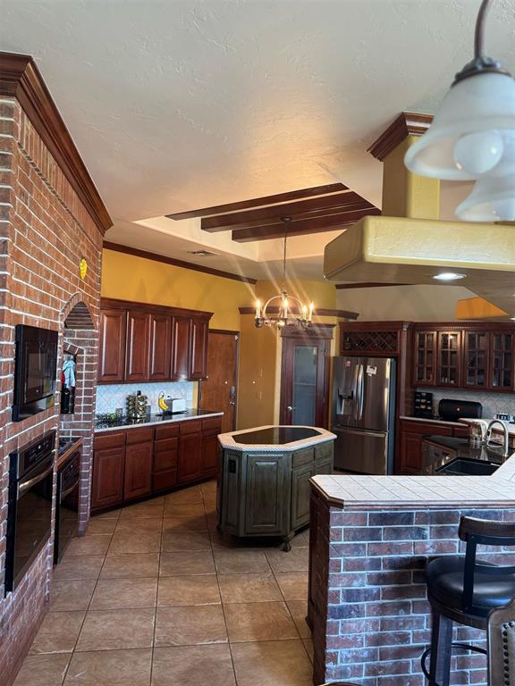 9209 SW 28th St, Oklahoma City, OK 73128 - kitchen with black appliances, decorative backsplash, tile counters, a center island, and light tile patterned flooring