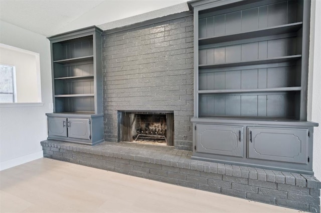 2322 Ripple Creek Ln, Edmond, OK 73012 - unfurnished living room featuring built in shelves, a fireplace, and wood finished floors