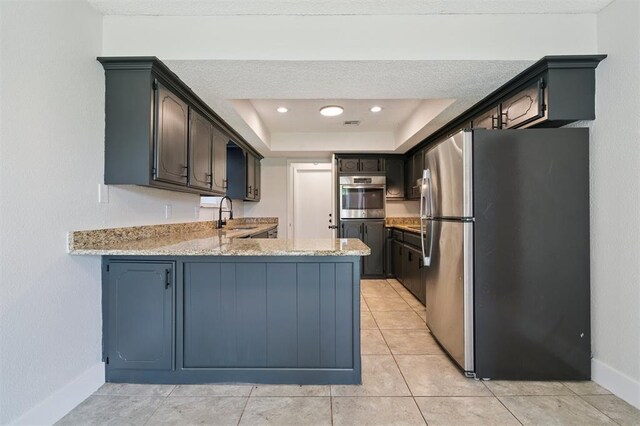 2322 Ripple Creek Ln, Edmond, OK 73012 - kitchen with freestanding refrigerator, a peninsula, light stone countertops, a tray ceiling, and light tile patterned floors