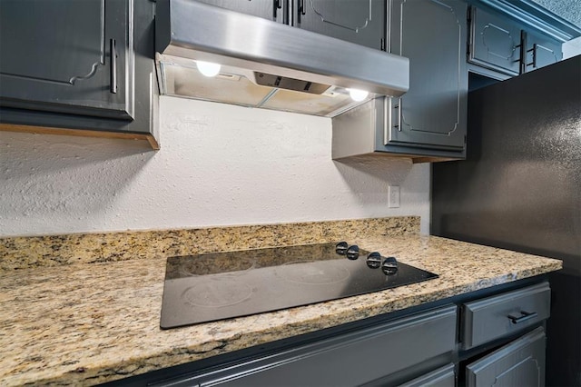 2322 Ripple Creek Ln, Edmond, OK 73012 - kitchen featuring under cabinet range hood, black electric stovetop, freestanding refrigerator, and light countertops