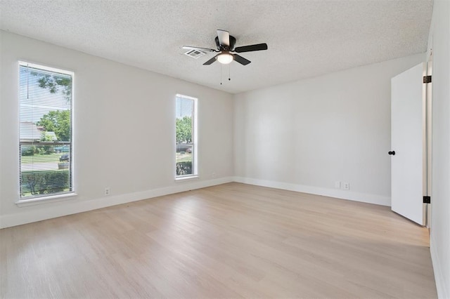 2322 Ripple Creek Ln, Edmond, OK 73012 - unfurnished room featuring light wood-style flooring, plenty of natural light, and a textured ceiling