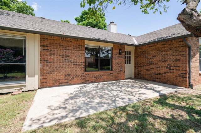 2322 Ripple Creek Ln, Edmond, OK 73012 - rear view of property with brick siding, a patio, a chimney, and a shingled roof