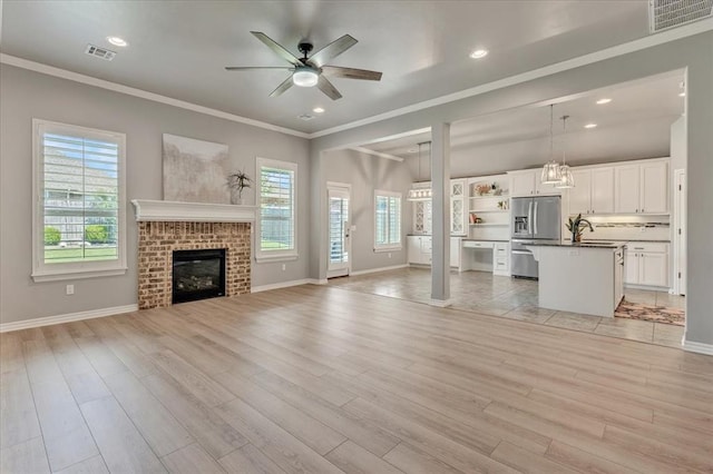 18608 Summer Grove Ave, Edmond, OK 73012 - unfurnished living room with ceiling fan, plenty of natural light, crown molding, light wood-style floors, and recessed lighting