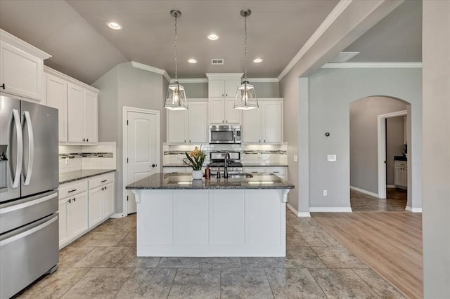 18608 Summer Grove Ave, Edmond, OK 73012 - kitchen with stainless steel appliances, arched walkways, dark stone counters, decorative backsplash, and ornamental molding