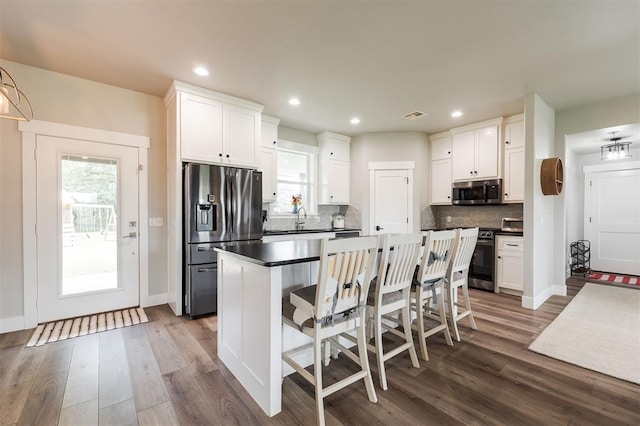 337030 E 1016th Rd, Meeker, OK 74855 - kitchen featuring appliances with stainless steel finishes, dark countertops, dark wood-type flooring, decorative backsplash, and white cabinetry