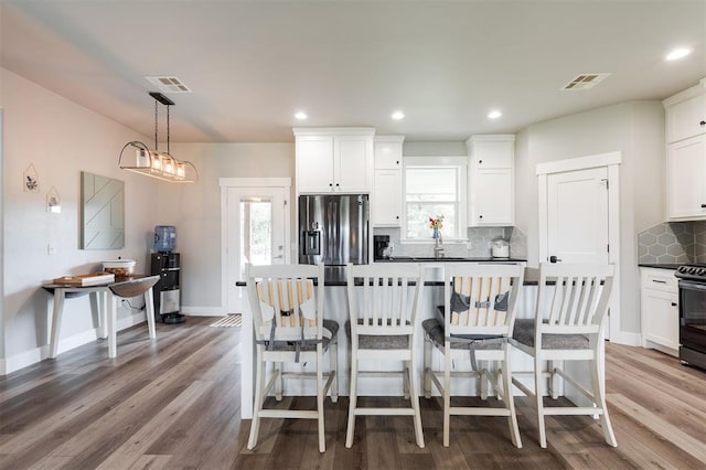 337030 E 1016th Rd, Meeker, OK 74855 - kitchen with appliances with stainless steel finishes, wood finished floors, white cabinetry, dark countertops, and recessed lighting