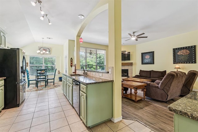 3751 Rock Dove Lndg, Edmond, OK 73034 - kitchen with green cabinets, stainless steel appliances, light tile patterned flooring, a tiled fireplace, and open floor plan