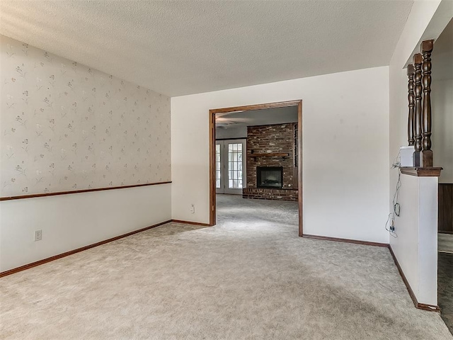 3000 Beverly Dr, Edmond, OK 73013 - empty room with carpet, a textured ceiling, wallpapered walls, and a fireplace