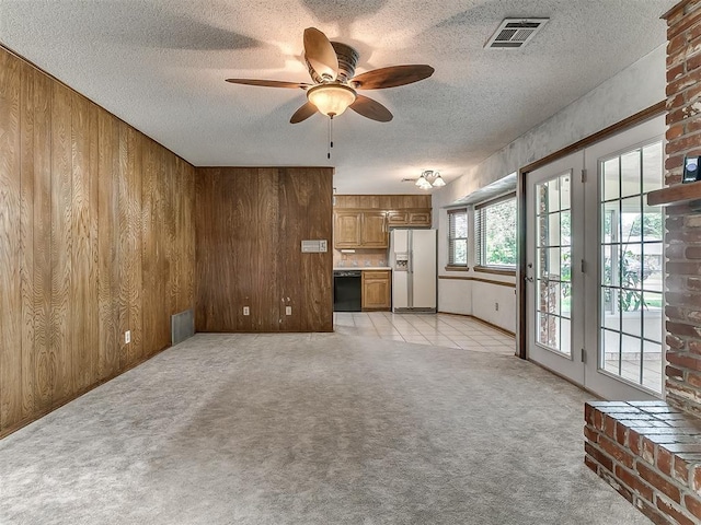 3000 Beverly Dr, Edmond, OK 73013 - unfurnished living room with light colored carpet, wooden walls, ceiling fan, and a textured ceiling