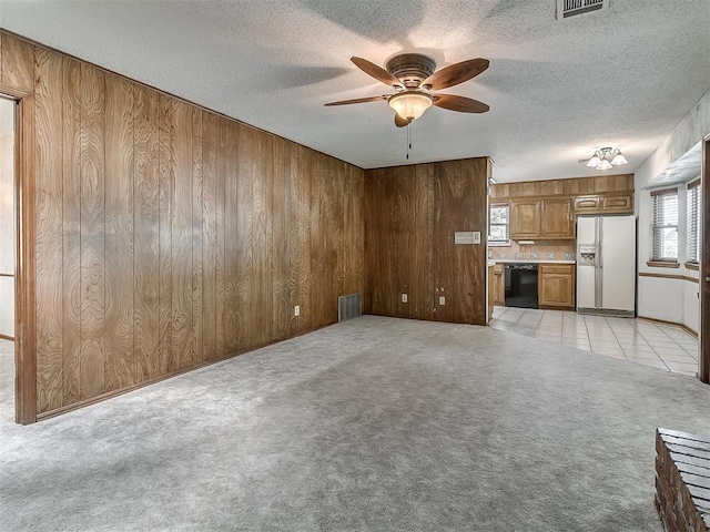 3000 Beverly Dr, Edmond, OK 73013 - unfurnished living room with ceiling fan, wooden walls, a textured ceiling, and light colored carpet