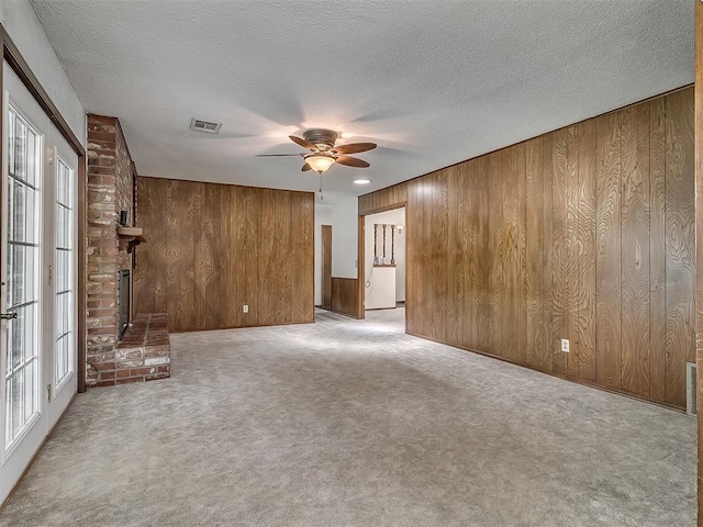 3000 Beverly Dr, Edmond, OK 73013 - unfurnished living room with wood walls, ceiling fan, carpet, and a textured ceiling