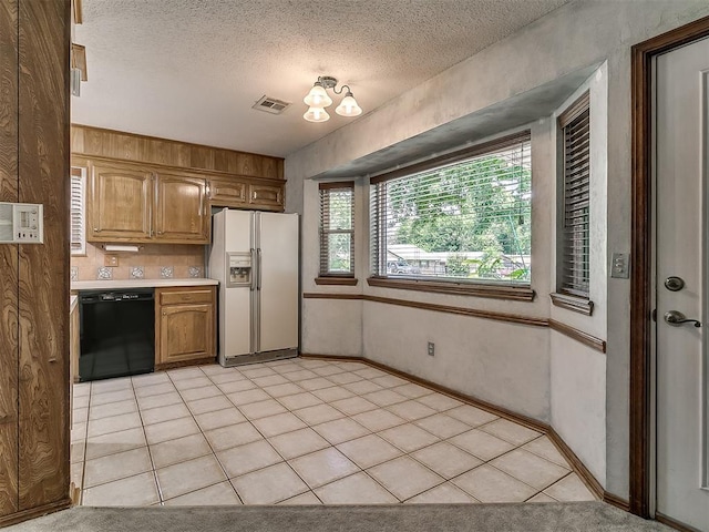 3000 Beverly Dr, Edmond, OK 73013 - kitchen featuring white refrigerator with ice dispenser, black dishwasher, light countertops, a textured ceiling, and brown cabinetry
