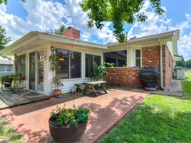 3000 Beverly Dr, Edmond, OK 73013 - back of house with a chimney, brick siding, a patio area, and a yard