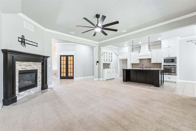 9041 NW 147th Ter, Yukon, OK 73099 - unfurnished living room with light carpet, a ceiling fan, a stone fireplace, crown molding, and light tile patterned floors