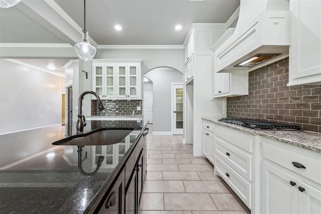 9041 NW 147th Ter, Yukon, OK 73099 - kitchen featuring custom range hood, stainless steel gas cooktop, tasteful backsplash, arched walkways, and white cabinets
