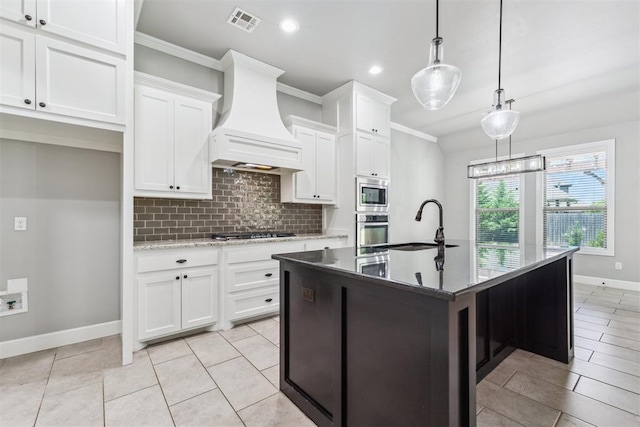 9041 NW 147th Ter, Yukon, OK 73099 - kitchen with appliances with stainless steel finishes, premium range hood, tasteful backsplash, a kitchen island with sink, and white cabinetry