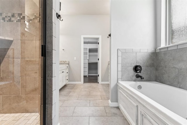 9041 NW 147th Ter, Yukon, OK 73099 - bathroom featuring a garden tub, a spacious closet, tile patterned flooring, vanity, and a stall shower