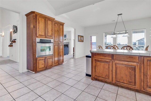 1045 Belmont Pl, Yukon, OK 73099 - kitchen featuring oven, brown cabinets, a fireplace, and light tile patterned floors