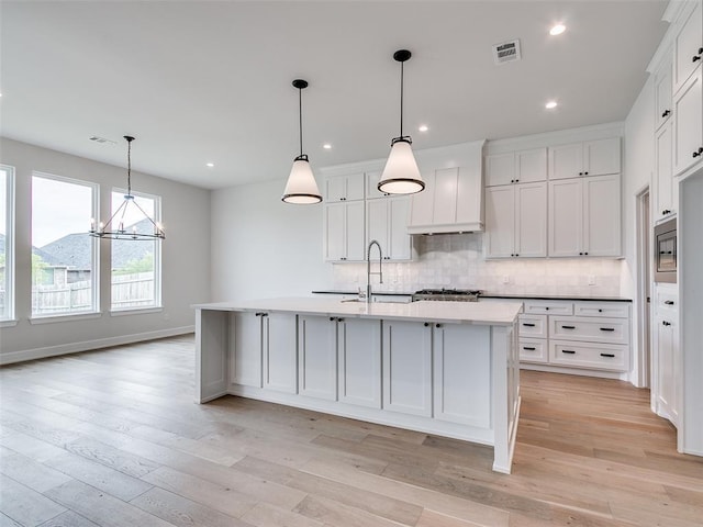 201 Pont Neuf Ct, Edmond, OK 73034 - kitchen with decorative backsplash, white cabinets, light wood-style floors, a kitchen island with sink, and recessed lighting