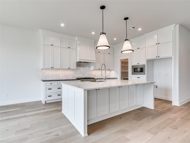 201 Pont Neuf Ct, Edmond, OK 73034 - kitchen featuring stainless steel microwave, premium range hood, light wood-style floors, backsplash, and recessed lighting