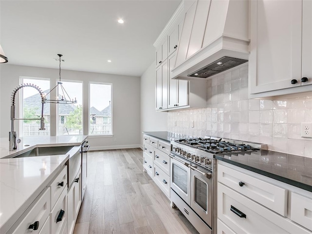 201 Pont Neuf Ct, Edmond, OK 73034 - kitchen featuring range with two ovens, premium range hood, a chandelier, dark stone countertops, and light wood-type flooring