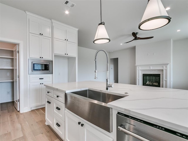 201 Pont Neuf Ct, Edmond, OK 73034 - kitchen with appliances with stainless steel finishes, light wood-type flooring, white cabinets, light stone countertops, and hanging light fixtures