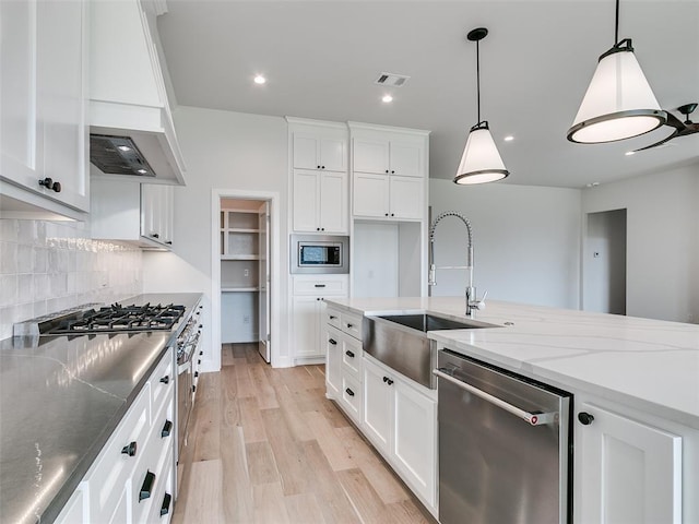 201 Pont Neuf Ct, Edmond, OK 73034 - kitchen featuring appliances with stainless steel finishes, light wood-style floors, white cabinetry, tasteful backsplash, and light stone countertops