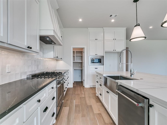 201 Pont Neuf Ct, Edmond, OK 73034 - kitchen featuring appliances with stainless steel finishes, custom exhaust hood, white cabinets, dark stone countertops, and decorative backsplash