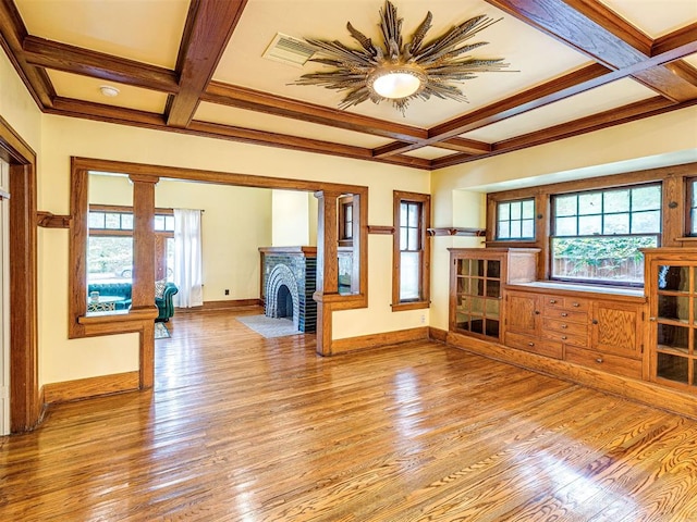 701 NW 21st St, Oklahoma City, OK 73103 - unfurnished living room featuring coffered ceiling, light wood-type flooring, beamed ceiling, a fireplace, and ornate columns