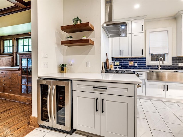 701 NW 21st St, Oklahoma City, OK 73103 - kitchen featuring wine cooler, wall chimney exhaust hood, ornamental molding, decorative backsplash, and white cabinets