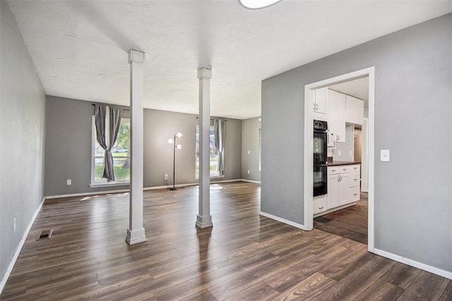 11904 Somerville Dr, Yukon, OK 73099 - unfurnished living room with dark wood finished floors and decorative columns