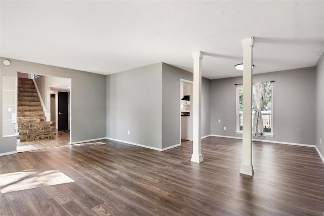 11904 Somerville Dr, Yukon, OK 73099 - unfurnished living room featuring dark wood finished floors, ornate columns, and stairway