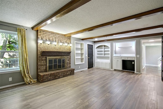 11904 Somerville Dr, Yukon, OK 73099 - unfurnished living room featuring a fireplace, a textured ceiling, beam ceiling, wood finished floors, and built in features