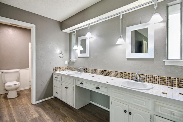 11904 Somerville Dr, Yukon, OK 73099 - full bathroom featuring wood finished floors, double vanity, decorative backsplash, a textured ceiling, and a textured wall