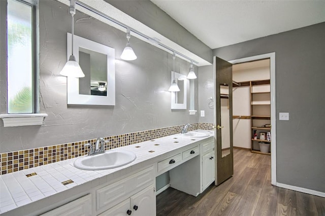 11904 Somerville Dr, Yukon, OK 73099 - full bathroom featuring double vanity, decorative backsplash, wood finished floors, a spacious closet, and plenty of natural light
